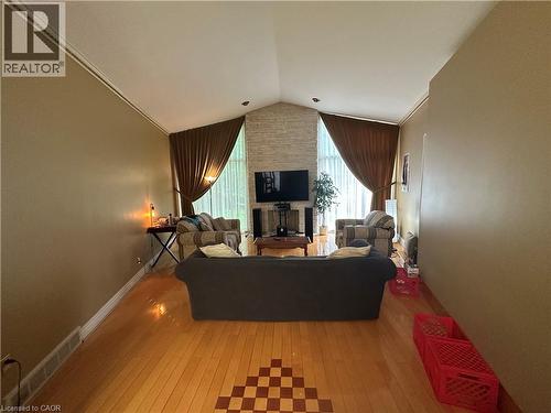 Spacious living area featuring a vaulted ceiling with crown molding, a stone-clad fireplace, and wood-finish flooring with a decorative inlay - 11 Wilmont Court, Hamilton, ON 