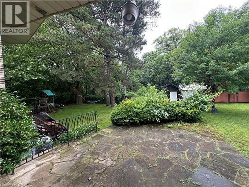 Expansive flagstone patio opening to a spacious lawn with mature trees, a storage shed, and a privacy fence - 11 Wilmont Court, Hamilton, ON 
