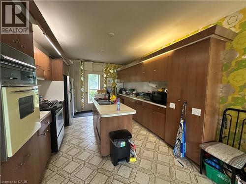 Kitchen featuring wood-finish cabinetry, a central island with an integrated sink, a built-in double oven, and a gas range - 11 Wilmont Court, Hamilton, ON 