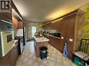 Kitchen featuring wood-finish cabinetry, a central island with an integrated sink, a built-in double oven, and a gas range - 11 Wilmont Court, Hamilton, ON 