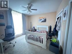 Carpeted room featuring a ceiling fan with light fixture, light-toned walls, and a window with light-blocking curtains - 