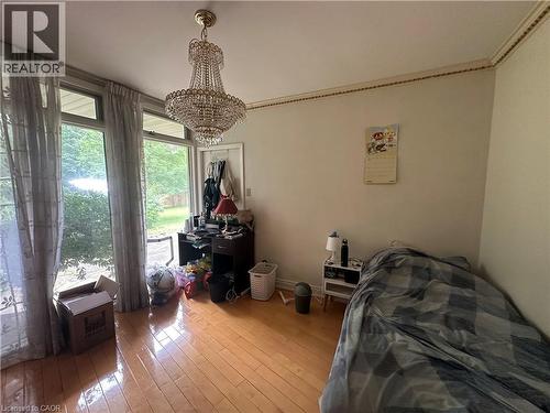 Room featuring wood-finish flooring, a crystal chandelier, and extensive fenestration with transom windows - 11 Wilmont Court, Hamilton, ON 