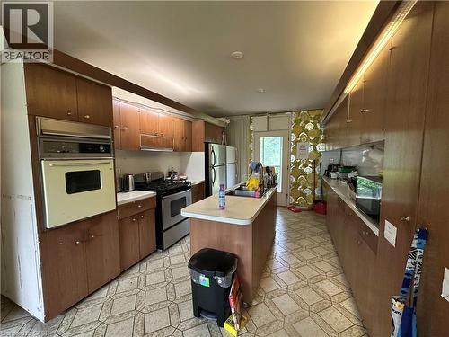 Galley kitchen featuring wood-finish cabinetry, a built-in oven, and a central island with an integrated sink - 11 Wilmont Court, Hamilton, ON 