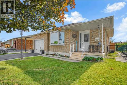 Brick exterior with a prominent bay window, attached garage, covered front porch, and a paved driveway - 234 Thunderbird Drive, Cambridge, ON 