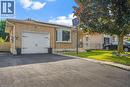 Brick facade residence featuring an attached garage with a decorative door, a paved driveway, and a front lawn with a mature tree - 234 Thunderbird Drive, Cambridge, ON 