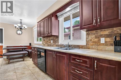Kitchen featuring rich wood-finish cabinetry, light-toned countertops, and a subway tile backsplash - 234 Thunderbird Drive, Cambridge, ON - Indoor Photo Showing Kitchen With Double Sink