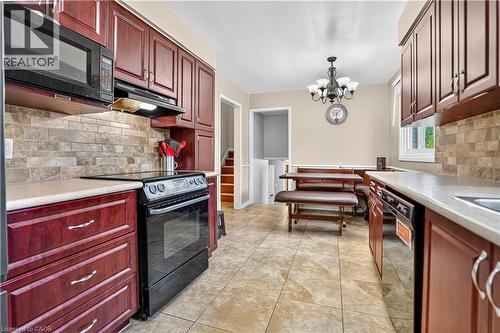 Kitchen featuring cherry-stained cabinetry, light-toned countertops, a tile backsplash, and tile flooring - 234 Thunderbird Drive, Cambridge, ON - Indoor Photo Showing Kitchen