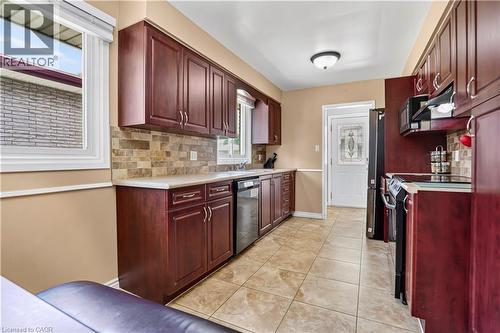 Kitchen featuring rich wood-finish cabinetry, tile flooring, a stone-look tile backsplash, and light countertops - 234 Thunderbird Drive, Cambridge, ON - Indoor Photo Showing Kitchen