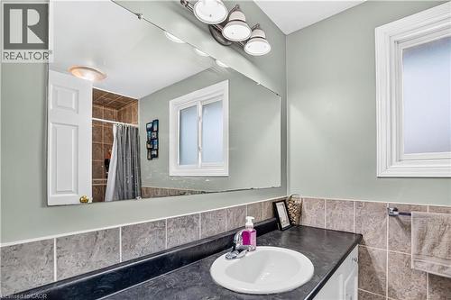 Bathroom vanity featuring an integrated sink, dark countertop, and tile backsplash - 234 Thunderbird Drive, Cambridge, ON - Indoor Photo Showing Bathroom