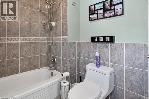 Bathtub with an integrated shower head and a tiled surround extending to the ceiling - 234 Thunderbird Drive, Cambridge, ON - Indoor Photo Showing Bathroom