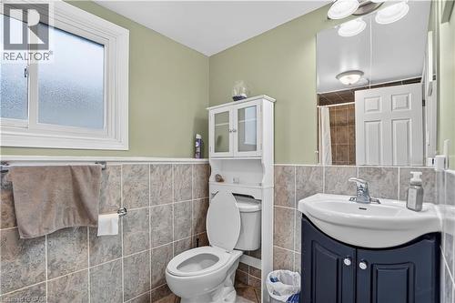 Bathroom featuring a tiled shower, frosted window, wall-mounted mirror, and a white toilet - 234 Thunderbird Drive, Cambridge, ON - Indoor Photo Showing Bathroom