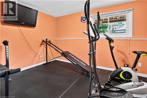 Dedicated interior space featuring resilient black flooring, a wall-mounted television, and a window with white trim - 234 Thunderbird Drive, Cambridge, ON - Indoor Photo Showing Gym Room