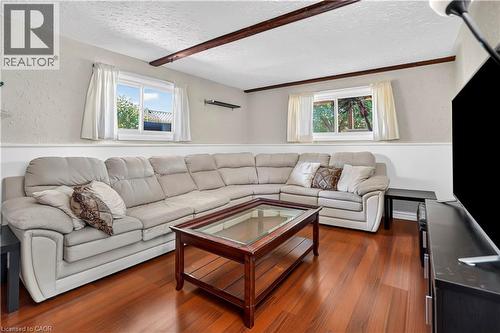 Living area featuring rich wood-finish flooring, white base molding, two windows, and exposed ceiling beams - 234 Thunderbird Drive, Cambridge, ON - Indoor Photo Showing Living Room