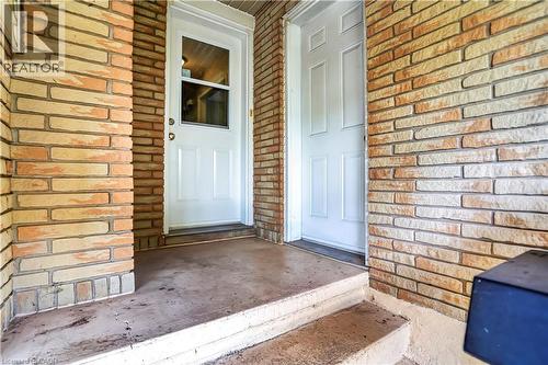 Brick facade with two white panel doors and a concrete porch - 234 Thunderbird Drive, Cambridge, ON - Outdoor With Exterior