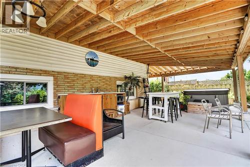 Expansive covered patio featuring a wood-beam ceiling, concrete flooring, and a built-in outdoor kitchen with sink - 234 Thunderbird Drive, Cambridge, ON - Outdoor With Deck Patio Veranda With Exterior