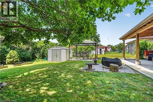 Expansive backyard featuring a manicured lawn, a covered patio area, and a separate paved section with a gazebo - 234 Thunderbird Drive, Cambridge, ON - Outdoor