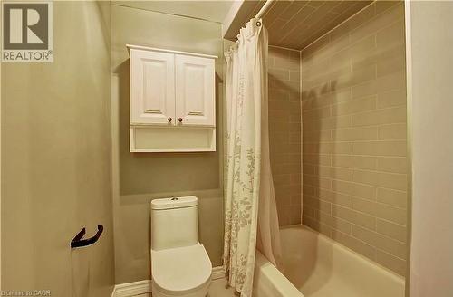 Bathroom featuring a white bathtub, subway tile surround, white toilet, and a wall-mounted white cabinet with decorative hardware - 599 Upper Horning Road Unit# Main/Upper, Hamilton, ON 