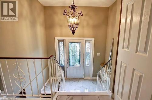 Foyer featuring a decorative wrought iron chandelier, white entry door with frosted glass panels, two sidelight windows, and marble-look tile flooring - 599 Upper Horning Road Unit# Main/Upper, Hamilton, ON 
