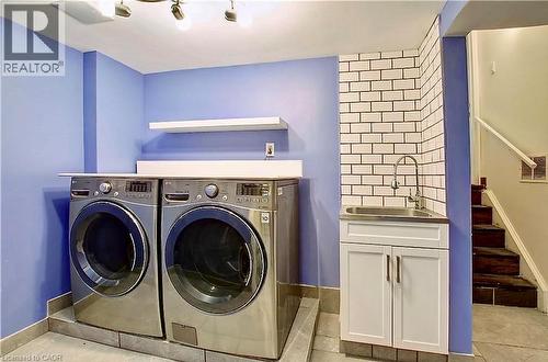 Dedicated laundry area featuring a utility sink with subway tile backsplash, white base cabinet, and floating wall shelving - 599 Upper Horning Road Unit# Main/Upper, Hamilton, ON 