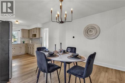 Dining area featuring a modern chandelier, light wood-finish flooring, and crisp white walls - 127 Acorn Crescent, London, ON 