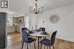 Dining area featuring a modern chandelier, light wood-finish flooring, and crisp white walls - 