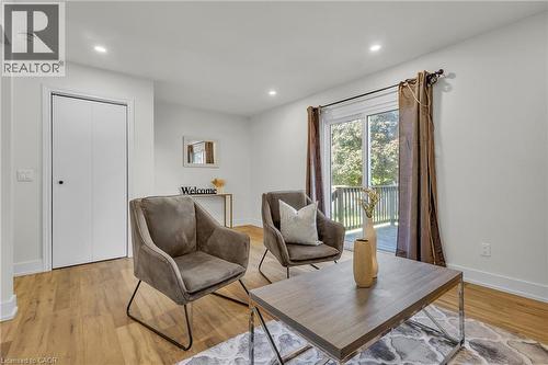 Bright interior space featuring wood-finish flooring, recessed lighting, white baseboards, a white bi-fold door, and sliding glass doors that open to an exterior deck - 127 Acorn Crescent, London, ON 