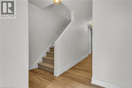 Staircase with light wood-finish treads and white risers, complemented by white wall paneling and a white handrail - 127 Acorn Crescent, London, ON 