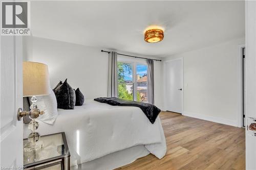 Spacious room featuring wood-finish flooring, white walls, and a large window with privacy curtains - 127 Acorn Crescent, London, ON 