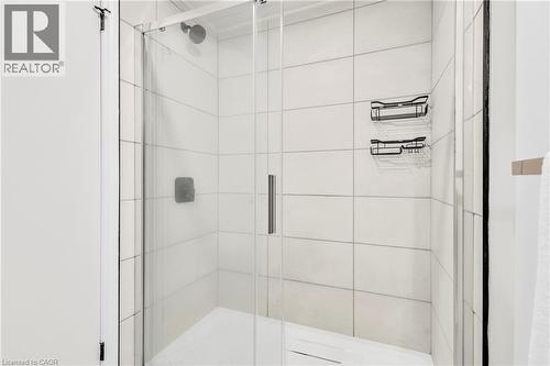 Glass-enclosed shower featuring white subway tile, a rain shower head, and matte black shower caddies - 127 Acorn Crescent, London, ON 