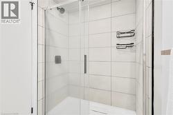 Glass-enclosed shower featuring white subway tile, a rain shower head, and matte black shower caddies - 