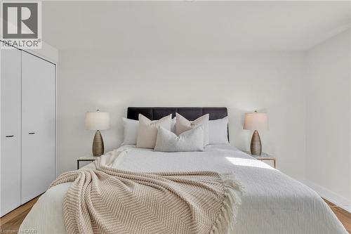 Bedroom featuring light wood-finish flooring, white walls, and a built-in closet with modern white doors - 127 Acorn Crescent, London, ON 