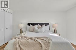 Bedroom featuring light wood-finish flooring, white walls, and a built-in closet with modern white doors - 