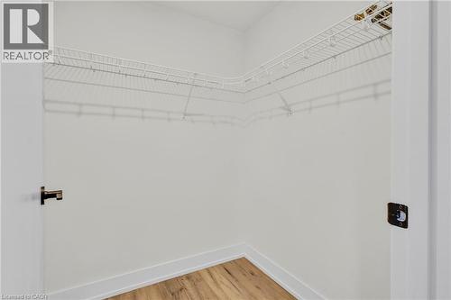Walk-in closet featuring white wire shelving, light wood-finish flooring, white baseboards, and white walls - 127 Acorn Crescent, London, ON 