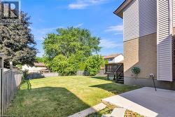 Expansive backyard featuring a manicured lawn, established trees, and a wooden privacy fence - 