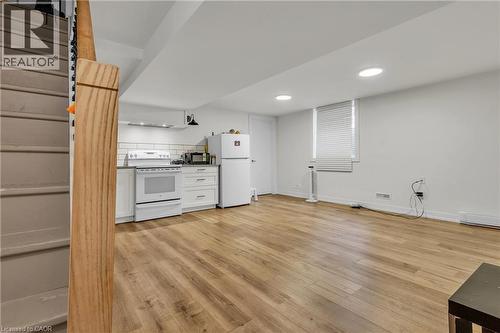 Open-concept living area featuring wood-finish flooring, recessed lighting, and a kitchen with white cabinetry and subway tile backsplash - 127 Acorn Crescent, London, ON 