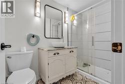 Bathroom featuring patterned floor tiles, a glass-enclosed shower with horizontal white wall tiles, and a white vanity with a vessel sink - 