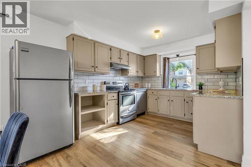 Kitchen featuring wood-finish flooring, tan cabinetry, light-toned countertops, white subway tile backsplash, and stainless steel appliances - 127 Acorn Crescent, London, ON 