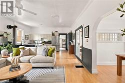 Open-concept living space featuring wood-finish flooring, white walls, and a ceiling fan - 