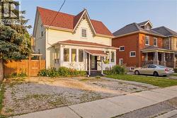 Traditional home featuring light-colored siding, a red shingled roof, a covered front porch, and a front sunroom - 