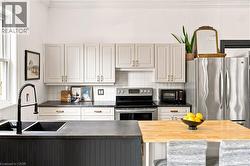 Modern kitchen featuring light-toned upper cabinetry and a dark-toned island with a butcher block extension - 