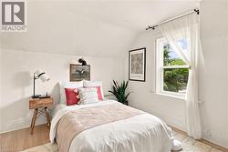 Bright room featuring a single hung window, sloped ceilings, and light-toned wood-finish flooring - 