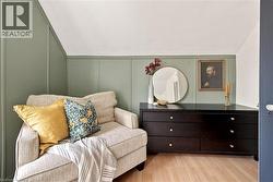 Attic room featuring light wood-finish flooring, accent wall with vertical paneling, and an angled ceiling - 