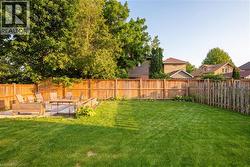 Expansive private backyard featuring a large grass lawn, perimeter wood fencing, and a paver patio with integrated wood planters - 