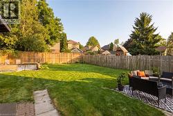 Spacious backyard featuring a manicured lawn, full privacy fencing, and two distinct patio areas - 