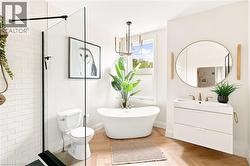 Contemporary bathroom featuring a freestanding tub, glass-enclosed shower with subway tile, and wood-finish herringbone flooring - 