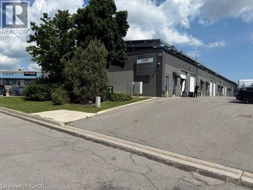 Industrial building featuring multiple garage bays, dark gray exterior paneling, and an asphalt parking lot - 95 Hempstead Drive Unit# 9, Hamilton, ON 