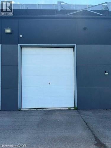 White roll-up door against a dark gray exterior paneling - 95 Hempstead Drive Unit# 9, Hamilton, ON 