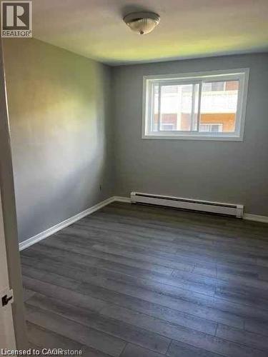 Room featuring wood-finish flooring, a white baseboard, light grey wall paint, and a window with white trim - 529 Parkside Drive Unit# 7, Waterloo, ON 