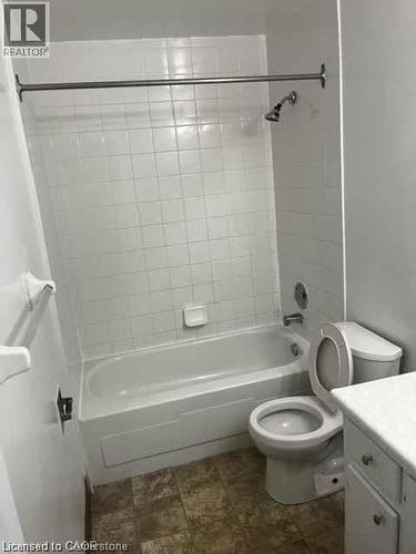 Bathroom featuring a white tiled shower surround, integrated bathtub, and a tile floor - 529 Parkside Drive Unit# 7, Waterloo, ON 