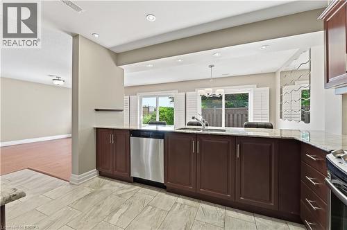 Kitchen featuring granite countertops, stainless steel dishwasher, dark wood cabinetry, recessed lighting, and tile flooring - 29 Archdeacon Clark Trail, Hamilton, ON 